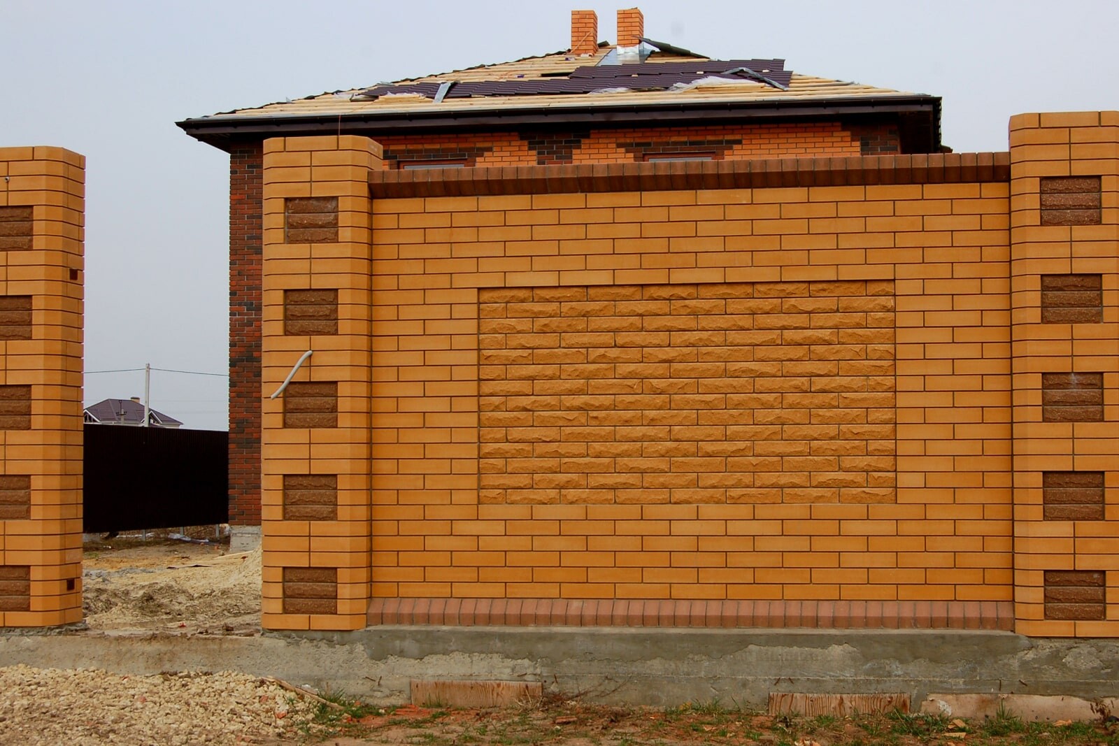 Высокий кирпичный забор с декоративными элементами